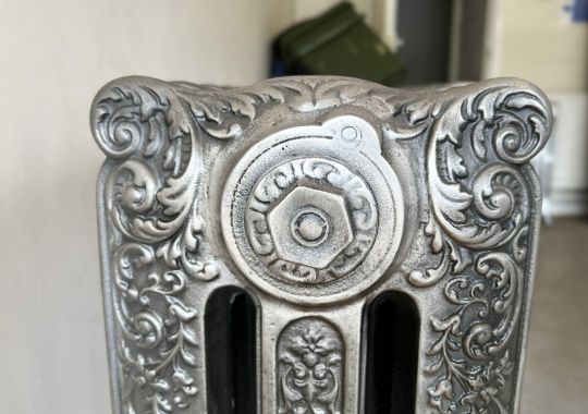 Close-up of a vintage radiator with ornate silver patterns, showcasing exquisite restoration work