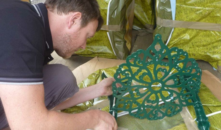 Artisan Dan meticulously restoring a detailed cast iron garden chair at Blast Spray Polish.