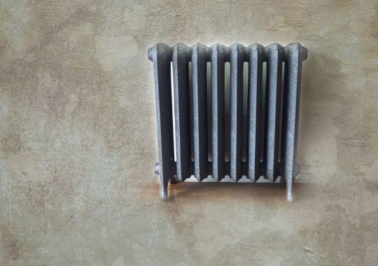 Vintage radiator with a detailed design against a textured wall, exemplifying classic style and restoration.