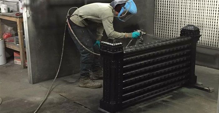 Professional restoring a vintage cast iron radiator with spray paint